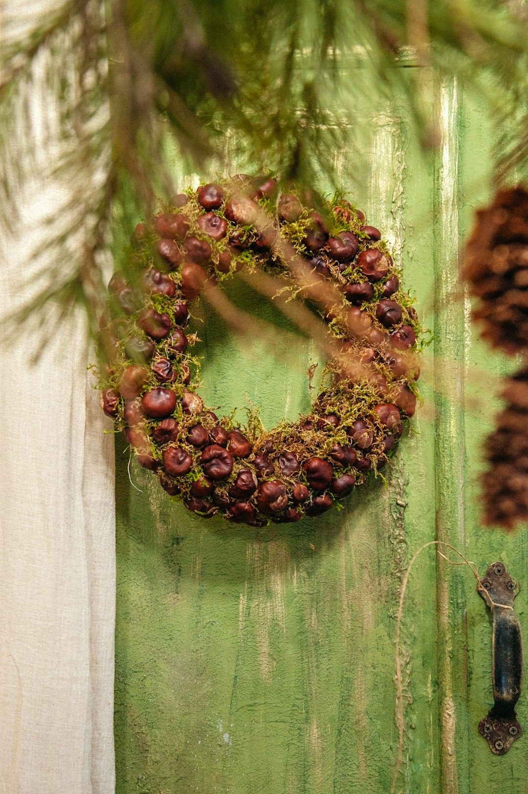 Chestnut and moss wreath hanging on a green wooden door