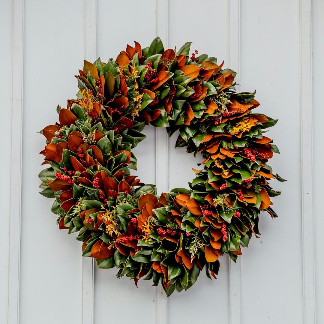 Magnolia leaf wreath with red berries on a white front door