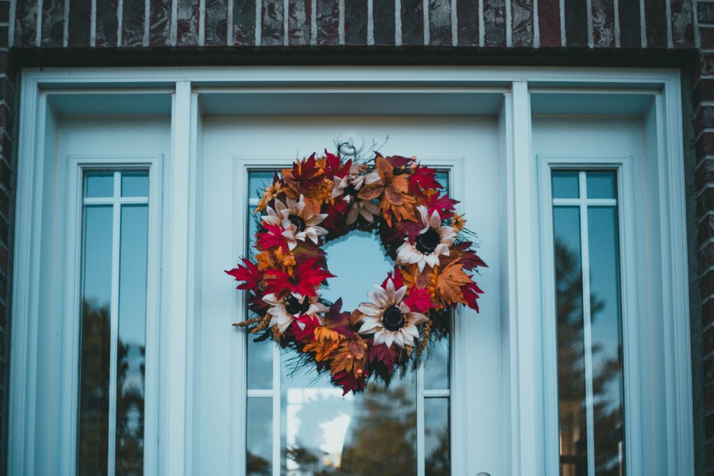 Colourful autumn leaf wreath with sunflowers on a light blue front door